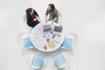 Alto ángulo ver a las mujeres de negocios hablando, reunión en la mesa redonda - foto de stock