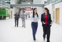 Businesswomen walking and talking in office lobby — Stock Photo