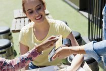 Young woman waitress with smart card at sunny sidewalk cafe — Stock Photo