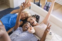 Portrait playful young women friends laying on bed — Stock Photo