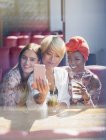 Mujeres jóvenes amigas tomando cócteles y posando para selfie en restaurante soleado - foto de stock