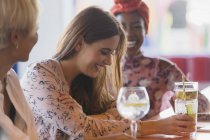 Молоді жінки друзі сміються, п'ють коктейлі в барі — стокове фото