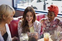Junge Freundinnen nutzen Smartphone und trinken Cocktails im Restaurant — Stockfoto