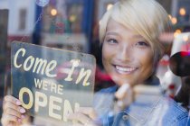 Portrait confident young female shop owner holding Open sign at window — Stock Photo