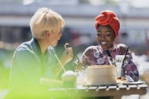 Mujeres jóvenes amigas disfrutando de dim sum almuerzo en la cafetería soleada acera - foto de stock