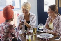 Young woman giving birthday gift to friend in restaurant — Stock Photo