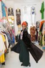 Retrato confiante, elegante jovem mulher experimentando casaco de pele na loja de roupas — Fotografia de Stock