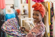 Retrato sorrindo, mulher jovem confiante em compras de lenço de cabeça na loja de roupas — Fotografia de Stock