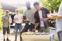 Masculino amigos aproveitando churrasco no ensolarado verão quintal — Fotografia de Stock