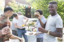Portrait smiling young man enjoying barbecue with friends — Stock Photo