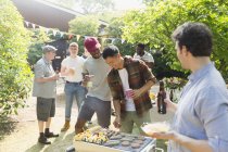 Männliche Freunde trinken Bier und grillen im sonnigen Sommergarten — Stockfoto