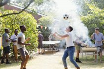 Чоловіки друзі грають у футбол і пінг-понг, насолоджуючись барбекю на задньому дворі — стокове фото