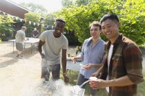 Retrato sorridente masculino amigos desfrutando verão quintal churrasco — Fotografia de Stock