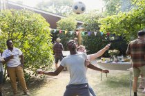 Чоловіки друзі грають у футбол, насолоджуючись літнім барбекю на подвір'ї — стокове фото