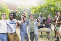 Happy, exuberant male friends drinking beer and singing during backyard barbecue — Stock Photo