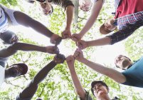 View from below mens group joining fists in circle, hiking under trees — Stock Photo