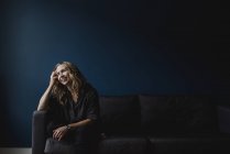 Щаслива жінка сидить на дивані, поглянувши — стокове фото