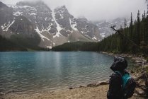 Randonneur serein en veste de pluie profitant d'une vue tranquille sur la montagne et le lac, Banff, Alberta, Canada — Photo de stock