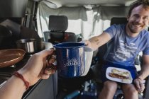 Personal perspective of couple toasting coffee cups in camper van — Stock Photo
