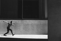 Hombre joven caminando en la soleada acera urbana - foto de stock