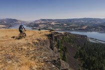 Man mountain biking on cliff along Columbia River, Hood River, Oregon, USA — Stock Photo