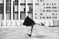 Hombre bailando con paraguas en la cabeza fuera de los edificios urbanos - foto de stock