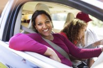 Portrait happy woman in car with family on road trip — Stock Photo