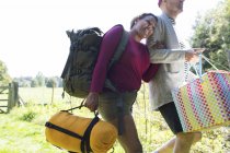 Affectionate couple carrying camping equipment — Stock Photo