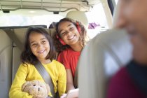 Happy sisters riding in back seat of car — Stock Photo