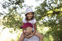 Padre cargando hija en hombros en el parque - foto de stock