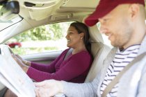 Couple with map driving in car on road trip — Stock Photo