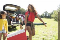 Sisters camping, carrying cooler in sunny field — Stock Photo
