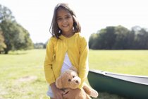 Portrait smiling, cute girl with teddy bear in sunny field — Stock Photo