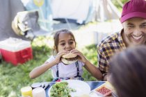 Father and daughter eating barbecue hamburgers at campsite — Stock Photo