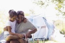 Mother helping daughter putting on shoes at campsite — Stock Photo