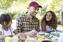 Happy father and daughters enjoying barbecue lunch — Stock Photo