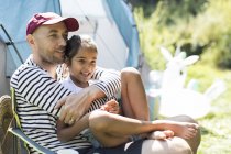 Padre cariñoso abrazando hija en el campamento soleado - foto de stock
