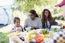 Happy family enjoying lunch at campsite table — Stock Photo