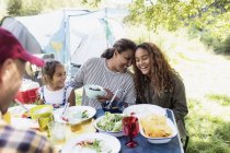 Famille affectueuse et heureuse déjeunant à table du camping — Photo de stock