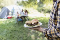 Pai servindo hambúrgueres de churrasco para a família no acampamento — Fotografia de Stock