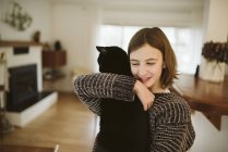 Chica cariñosa sosteniendo gato negro - foto de stock