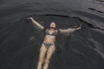 Sereno jovem mulher de biquíni flutuando no lago — Fotografia de Stock