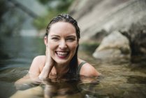 Porträt lächelnde, schöne junge Frau, die im See schwimmt — Stockfoto