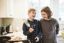 Happy brother and sister making pancakes in kitchen — Stock Photo