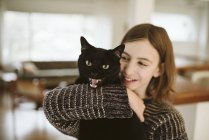 Retrato chica sosteniendo silbido negro gato - foto de stock