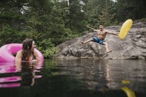 Verspielter junger Mann mit aufblasbarem Ring, der in einen entlegenen See springt, Squamish, Britisch Columbia, Kanada — Stockfoto
