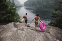 Young couple with inflatable rings at remote lakeside, Squamish, British Columbia, Canada — Stock Photo