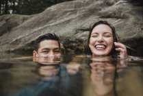 Retrato juguetona pareja joven nadando en el lago - foto de stock