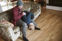 Грайливий батько тримає сина догори ногами на дивані у вітальні — стокове фото