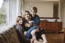 Портрет щасливої матері та дітей, що сміються на дивані у вітальні — стокове фото